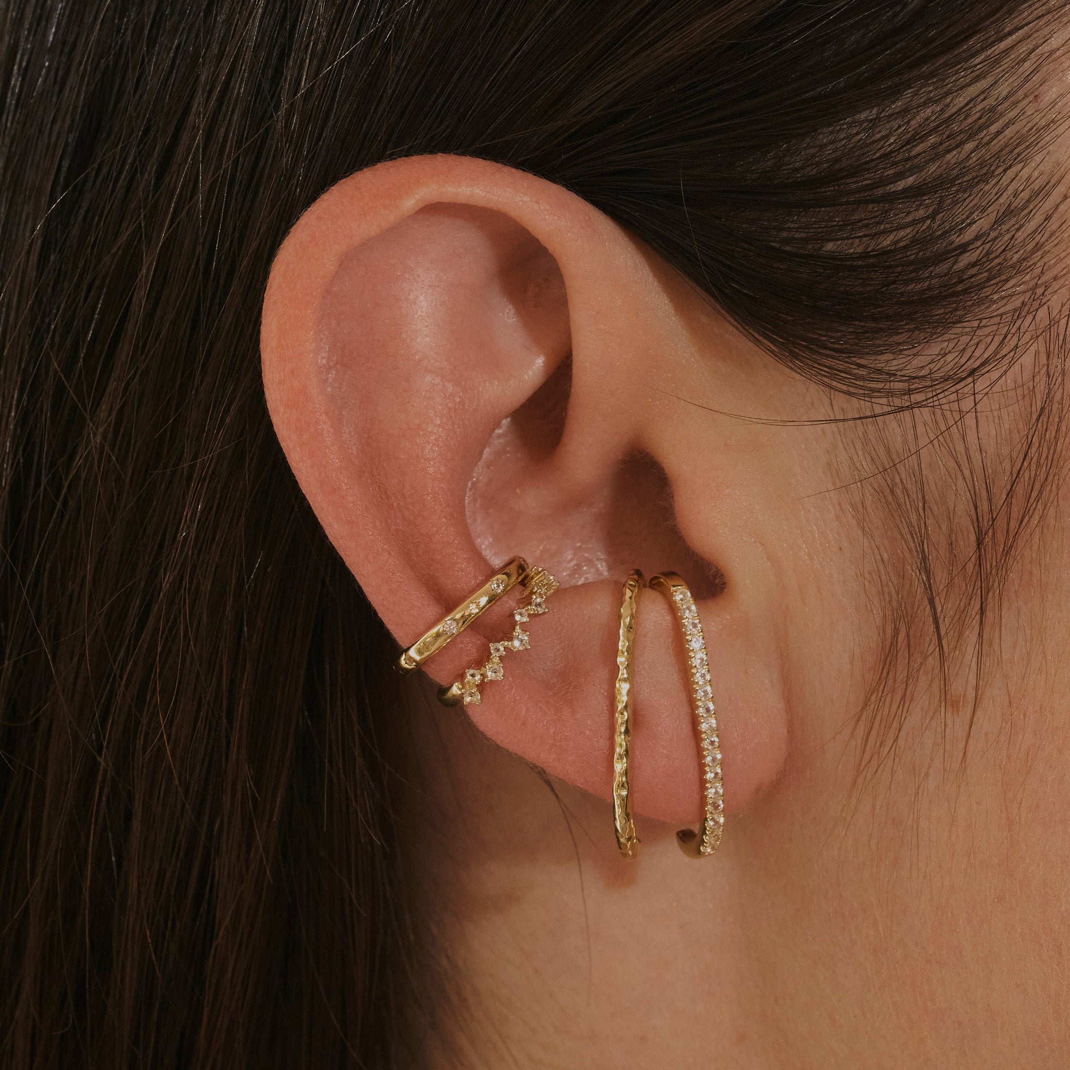 model wearing suspender earrings in 14k gold vermeil along with ear cuffs including the White Sapphire Celestial Ear Cuff 14k Gold Vermeil
