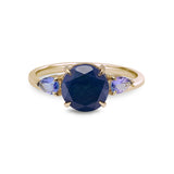 Gold ring with a blue gemstone and smaller purple stones on a white background