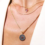 Close-up of a person wearing two gold necklaces with pendants on a light background