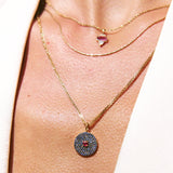 Close-up of a person wearing two gold necklaces with pendants on a light background