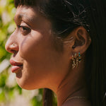 model wearing solid gold earrings including the Snake Huggie 9k Gold
