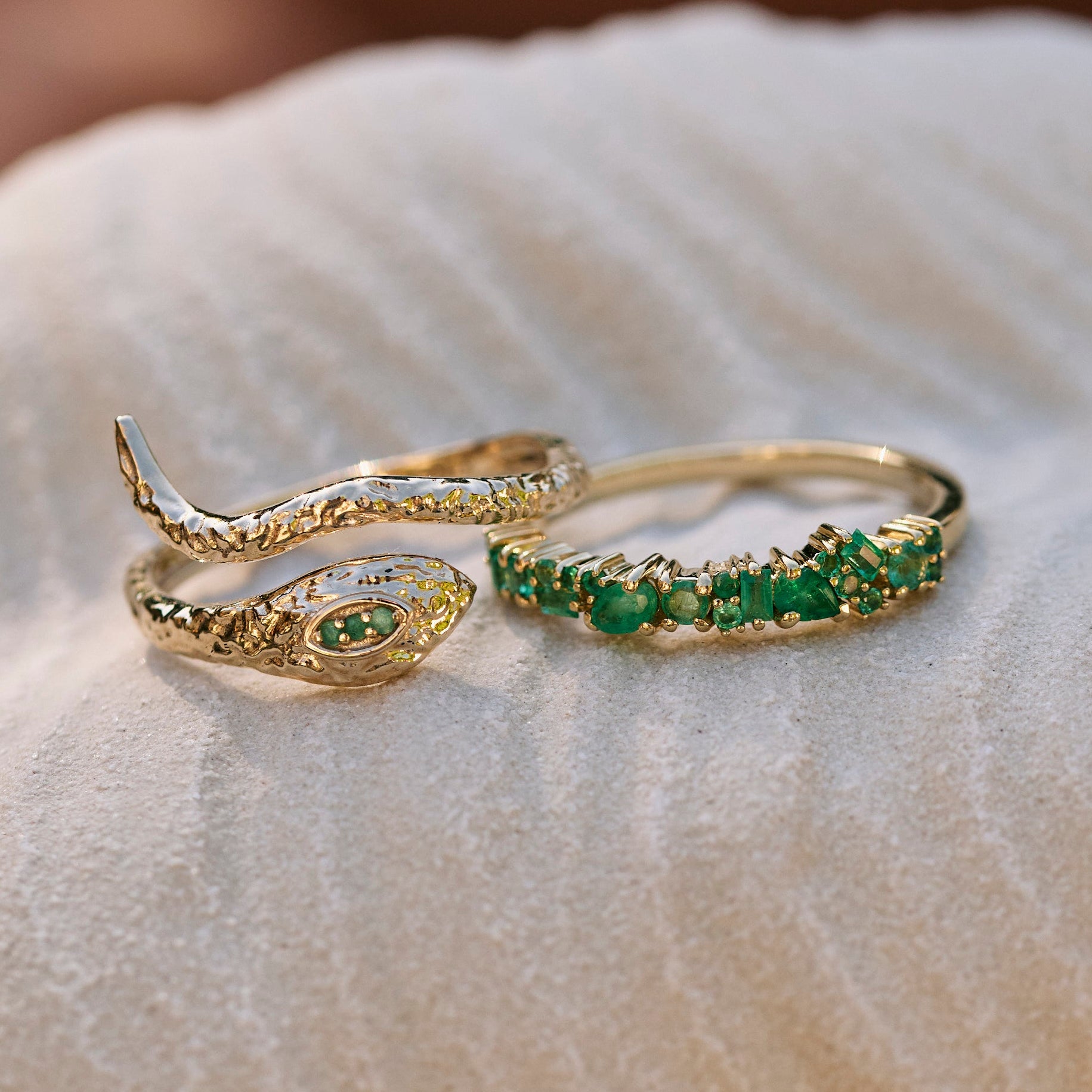 Snake Ring 9k Gold and emerald ring on textured surface