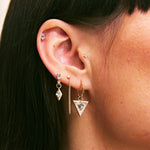 Close-up of an ear with multiple earrings on a blurred background
