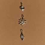 Three gold pendants with gemstones on a brown background