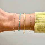 model wrist showing the Station Bead Chain Bracelet 9k Gold along with other solid gold bracelets including the twisted gold bracelet