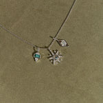 Necklace with star-shaped pendant and green gemstone on a green background