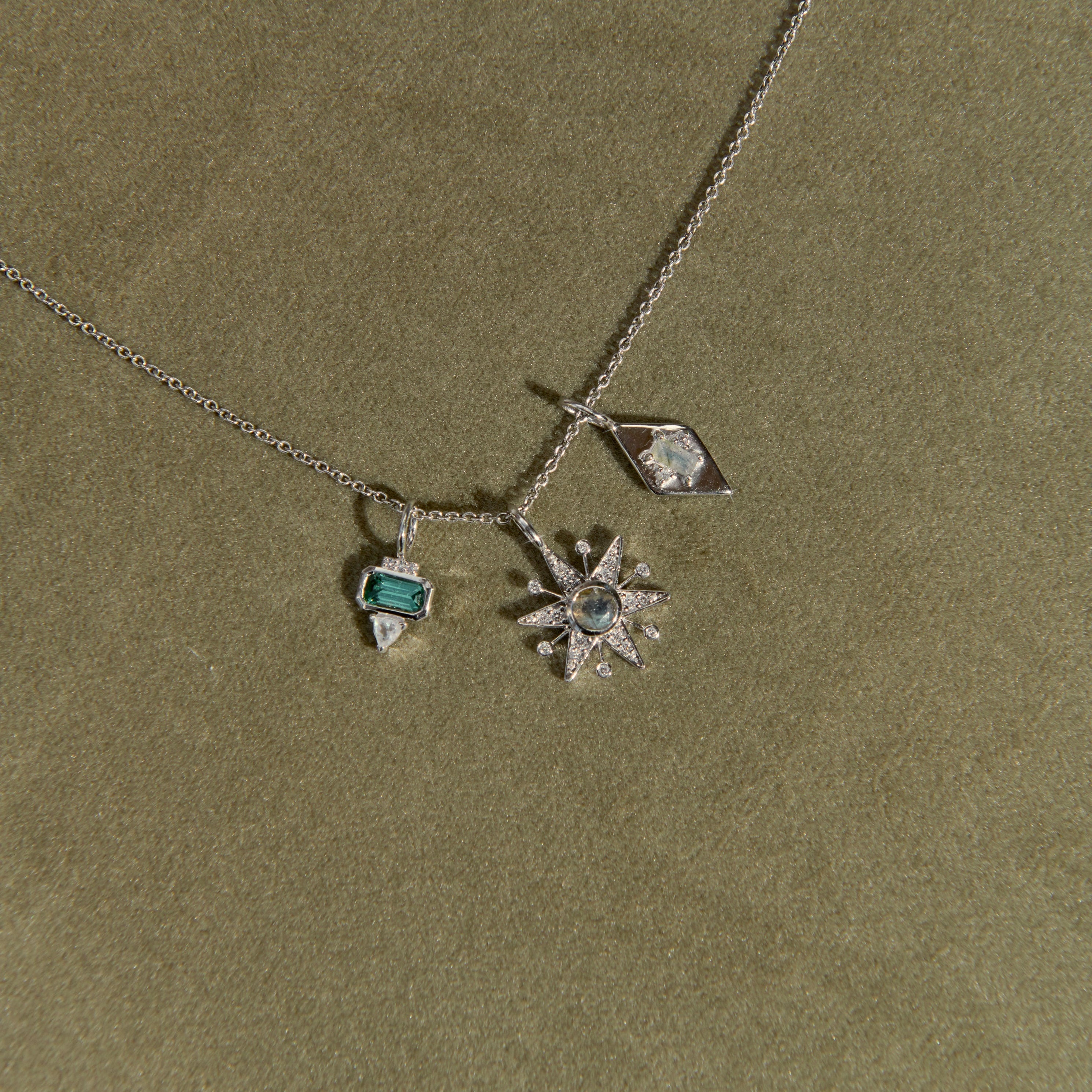 Necklace with star-shaped pendant and green gemstone on a green background