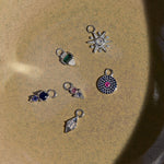 Collection of silver earring charms with gemstones on a textured beige surface