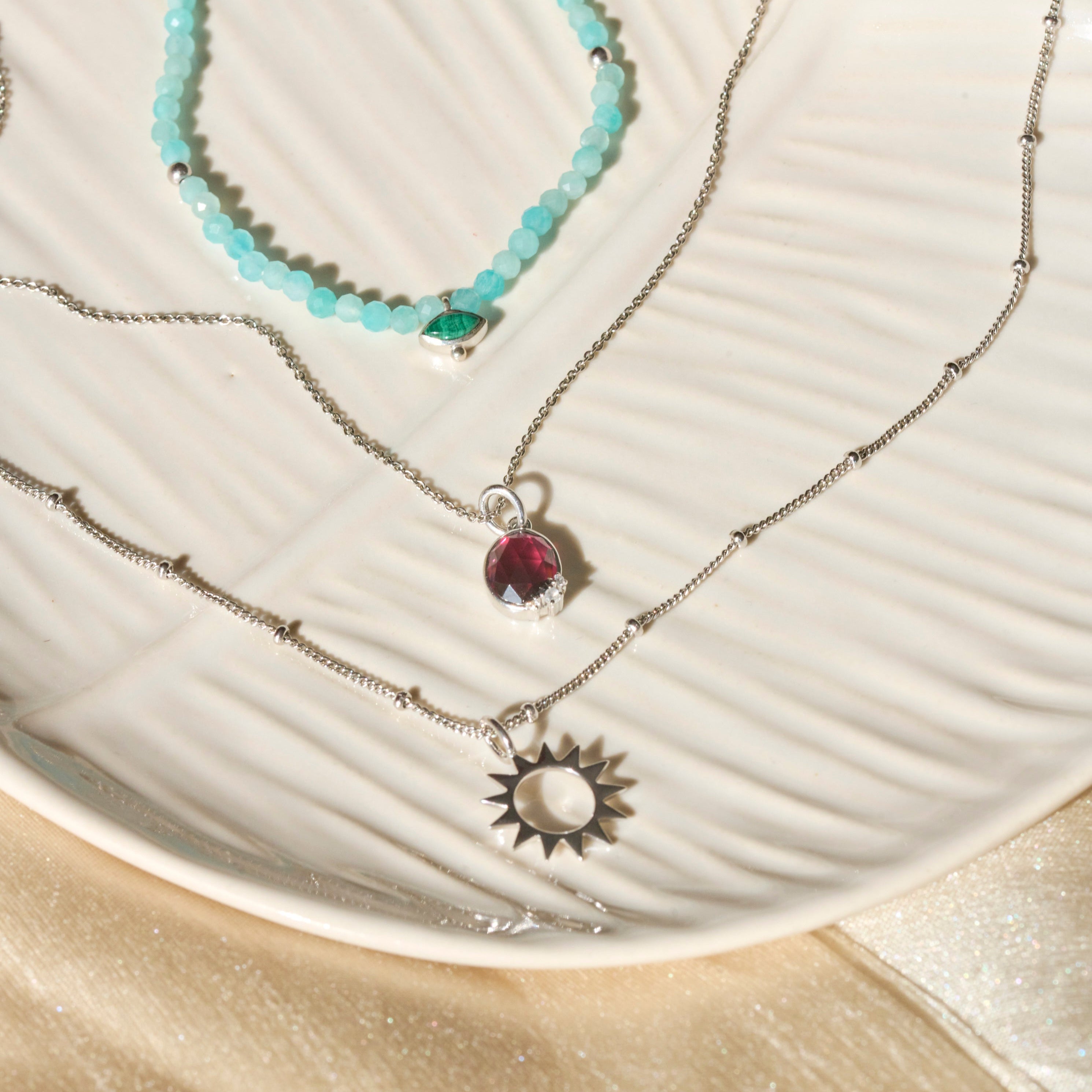 sterling silver necklaces displayed on porcelain dish including the Sunburst Silhouette Pendant Sterling Silver
