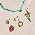 solid gold pendants displayed on hard surface including the Sunburst Silhouette Pendant 9k Gold 