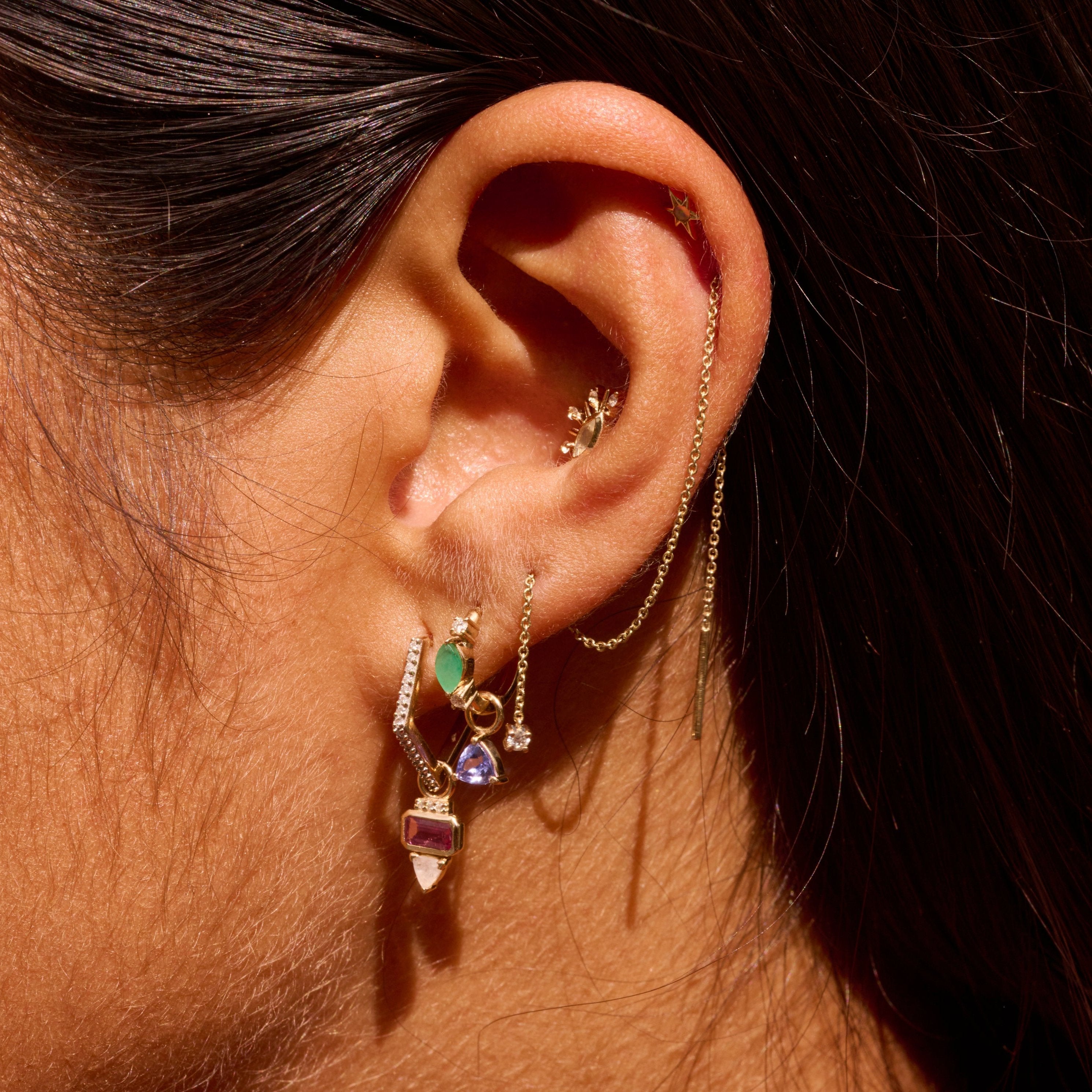 close up of solid gold earrings including the Tanzanite Trillion Earring Charm 9k Gold