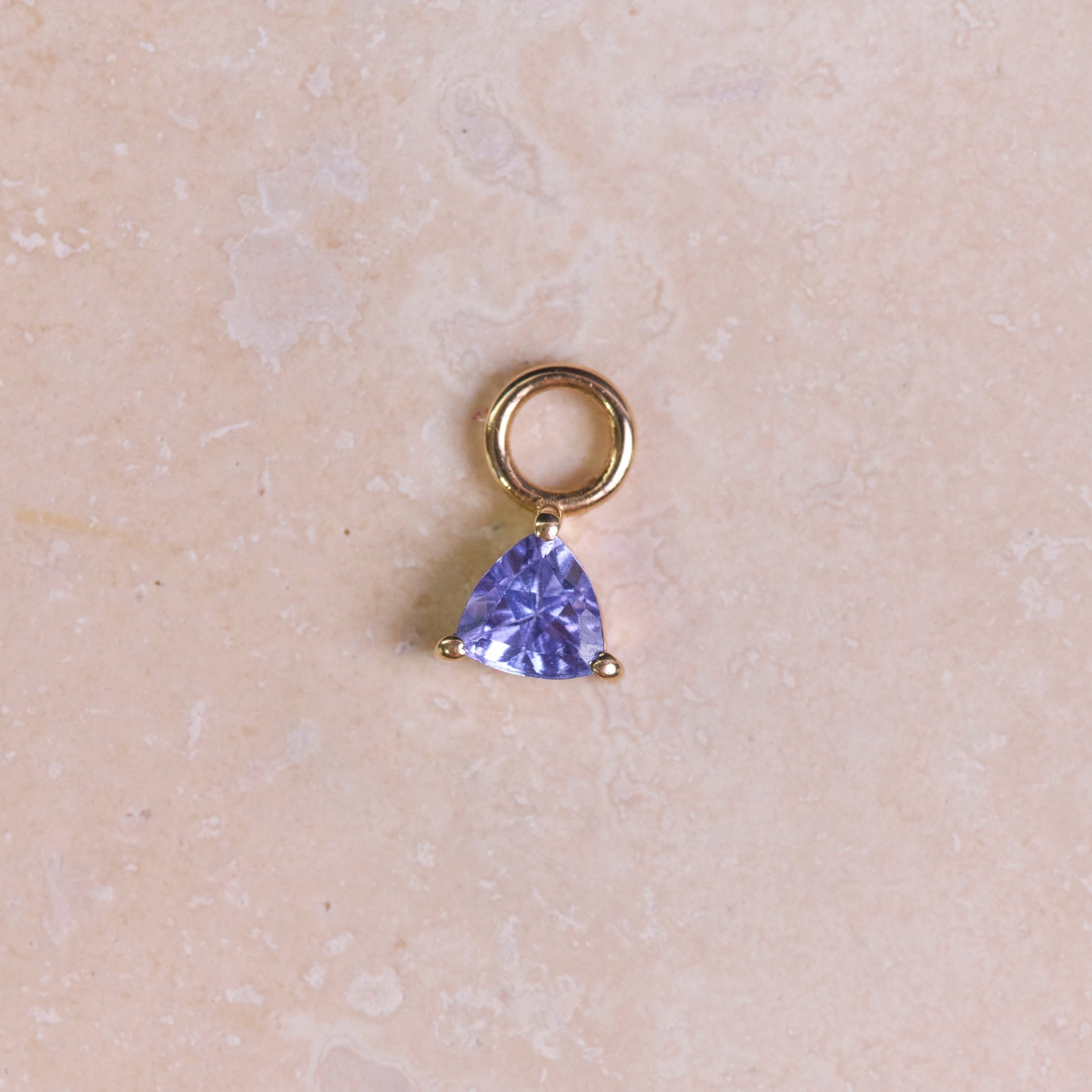 Tanzanite Trillion Earring Charm 9k Gold on hard surface