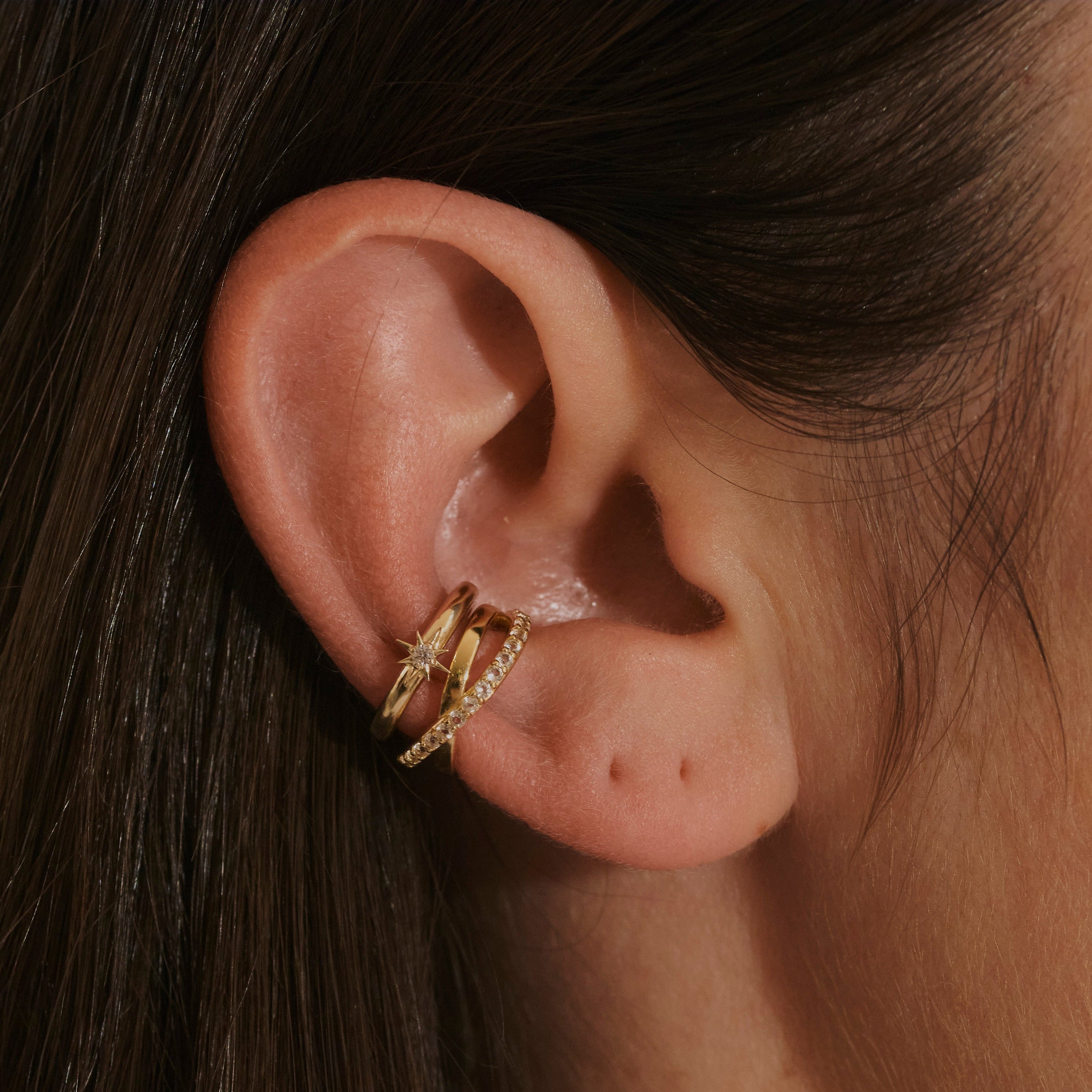 model ear wearing 14k gold vermeil ear cuffs including the Topaz Crossover Ear Cuff 14k Gold Vermeil