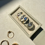 Set of rings displayed on a light gray surface with a jewelry box.