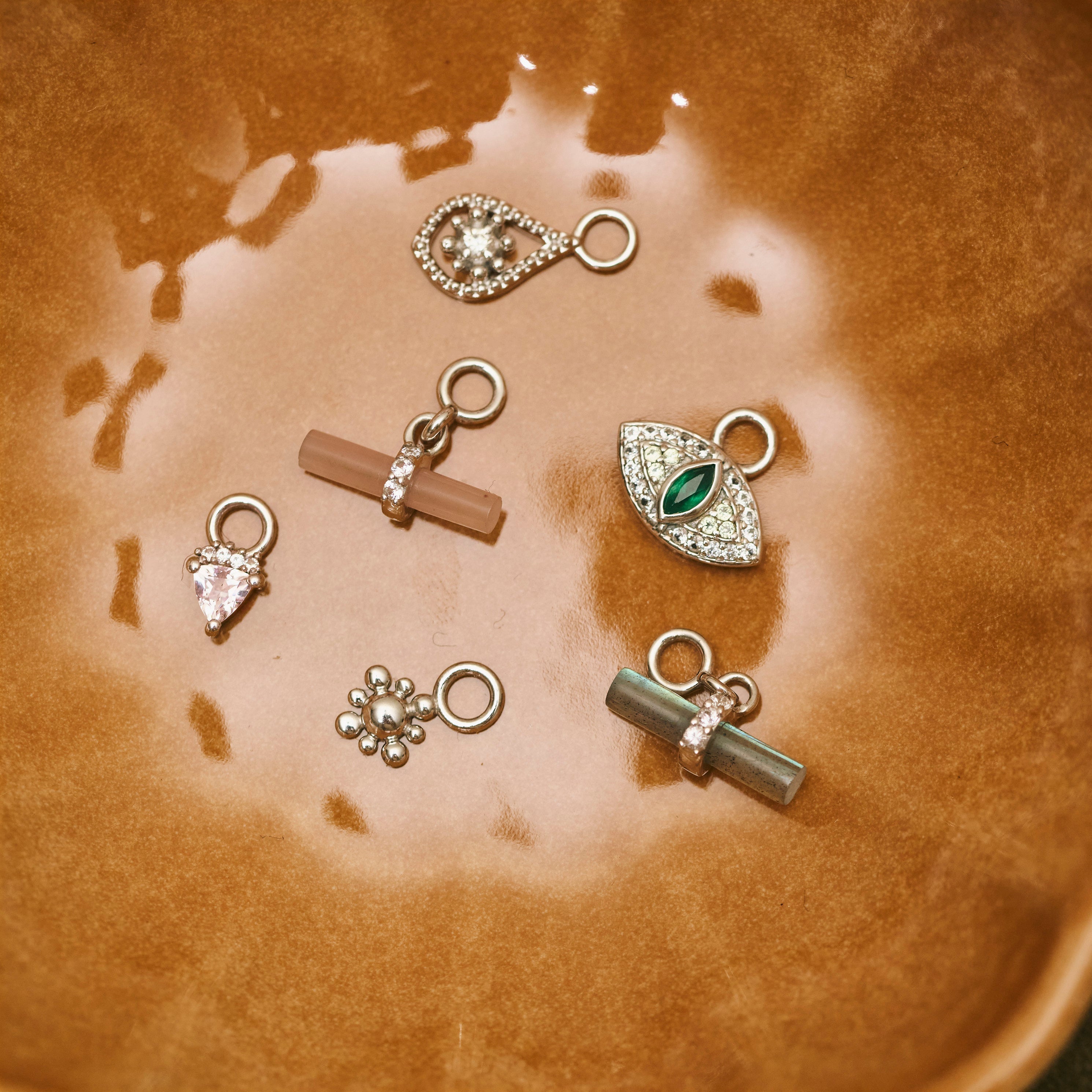 sterling silver earring charms on a porcelain dish including the White Sapphire & Morganite Trillion Necklace Sterling Silver