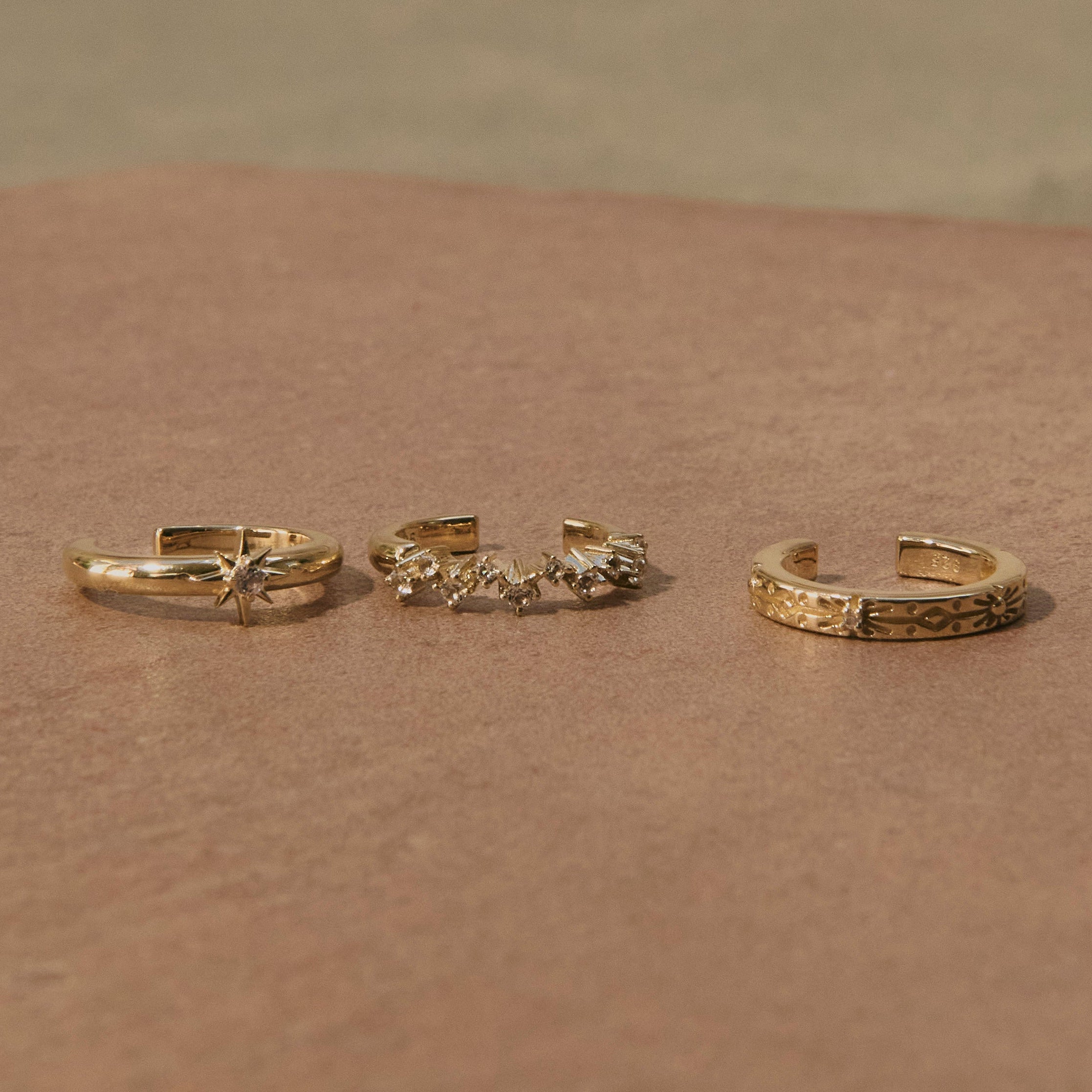 White Sapphire Starburst Ear Cuff 14k Gold Vermeil displayed on stone surface along with other 14k gold vermeil ear cuffs