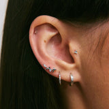 Close-up of an ear with multiple silver earrings against a blurred background