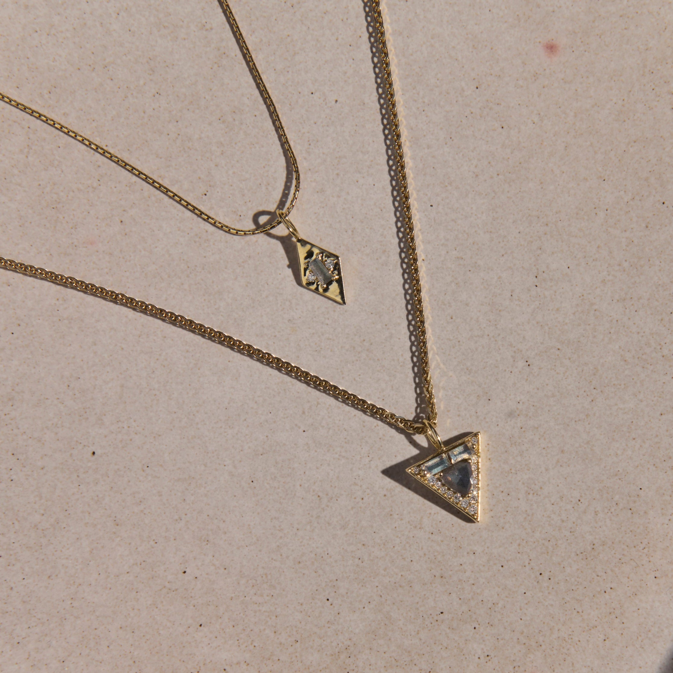 Gold necklace with a triangle pendant on a beige plate