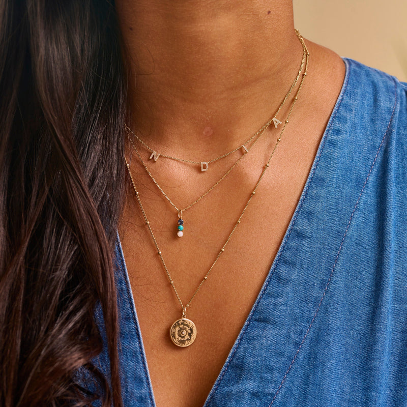 Model wearing 9k solid gold necklaces layered  including the Personalised Diamond Initial Necklace 9k Gold