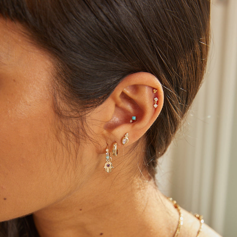 model ear wearing gold earrings including Moonstone & Diamond Tear Drop Stud Earring 9k Gold