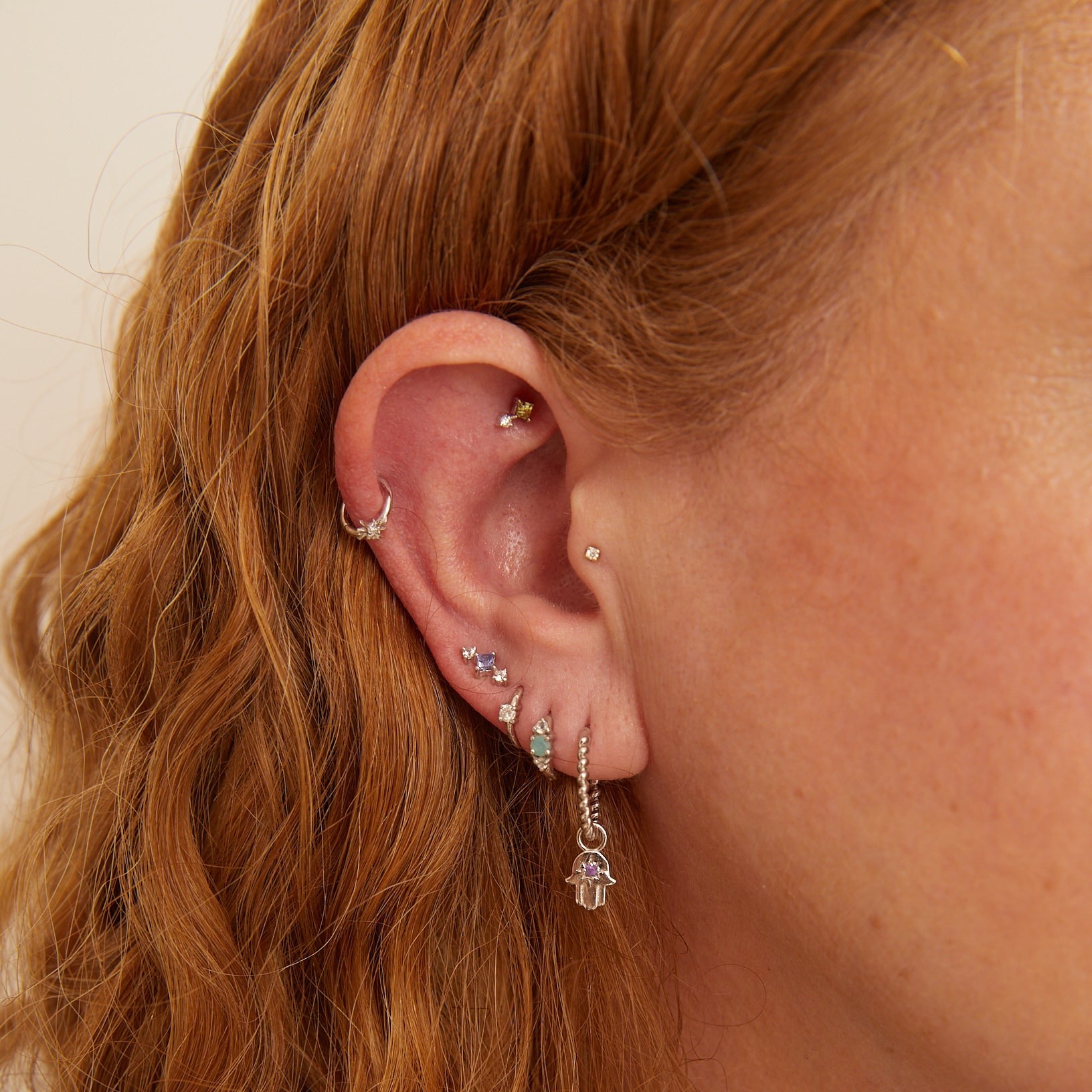 model wearing solid gold earring stack including the Medium Twisted Huggie Hoop Earring 9k Gold