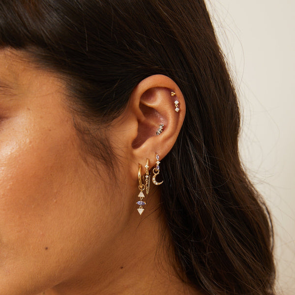 model wearing solid gold earring stack including the Diamond Moon Chain Huggie Hoop Earring 9k Gold