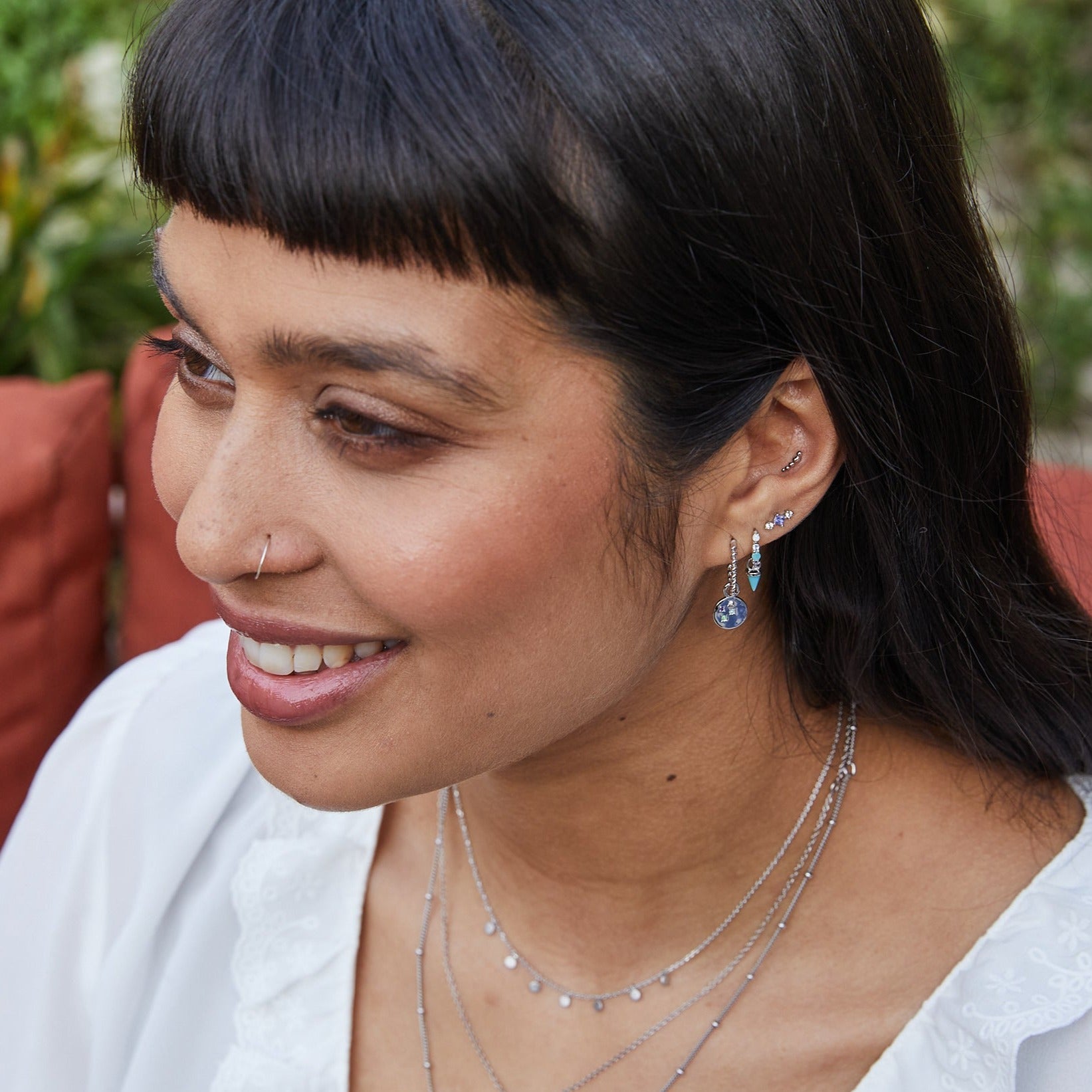 model wearing sterling silver earring stack including the Medium Twisted Huggie Hoop Earring Sterling Silver