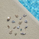 solid gold and sterling silver earring charm display by the pool