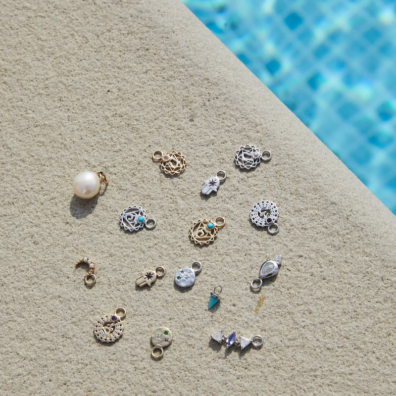 chakra charms in solid gold and sterling silver by the poolsolid gold and sterling silver earring charm display by the pool