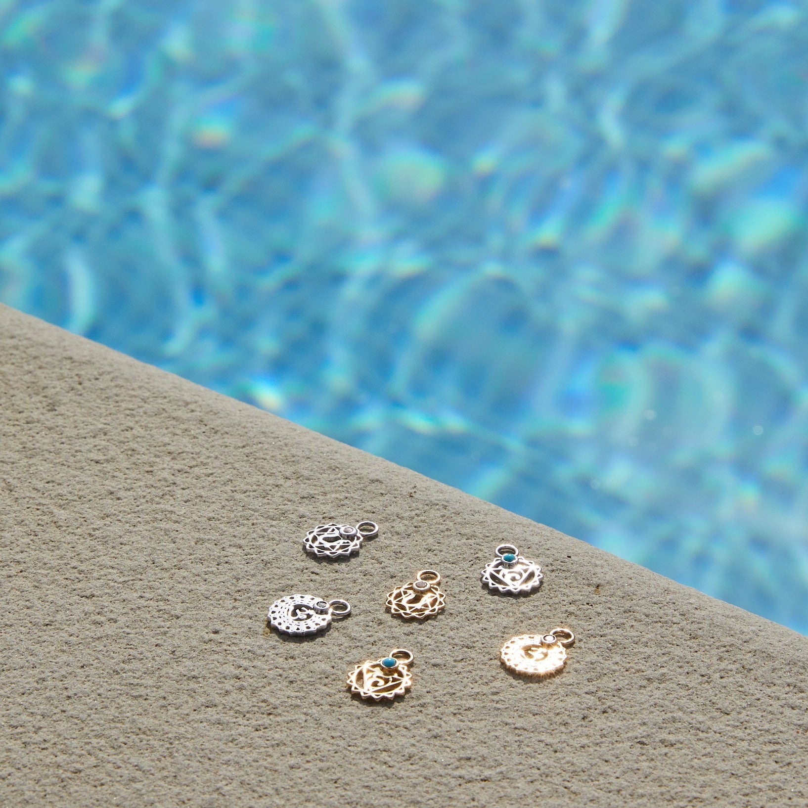 chakra charms in solid gold and sterling silver by the pool