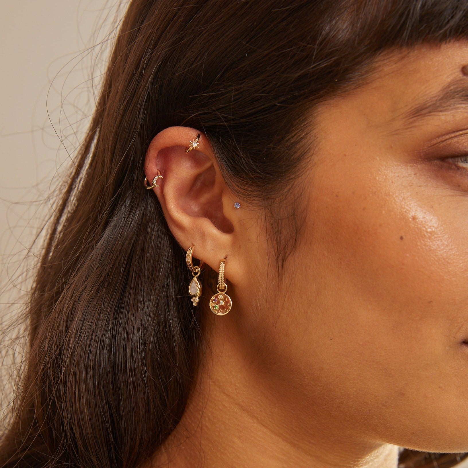 model wearing earring stack including the Leaf Huggie Hoop Earring 9k Gold