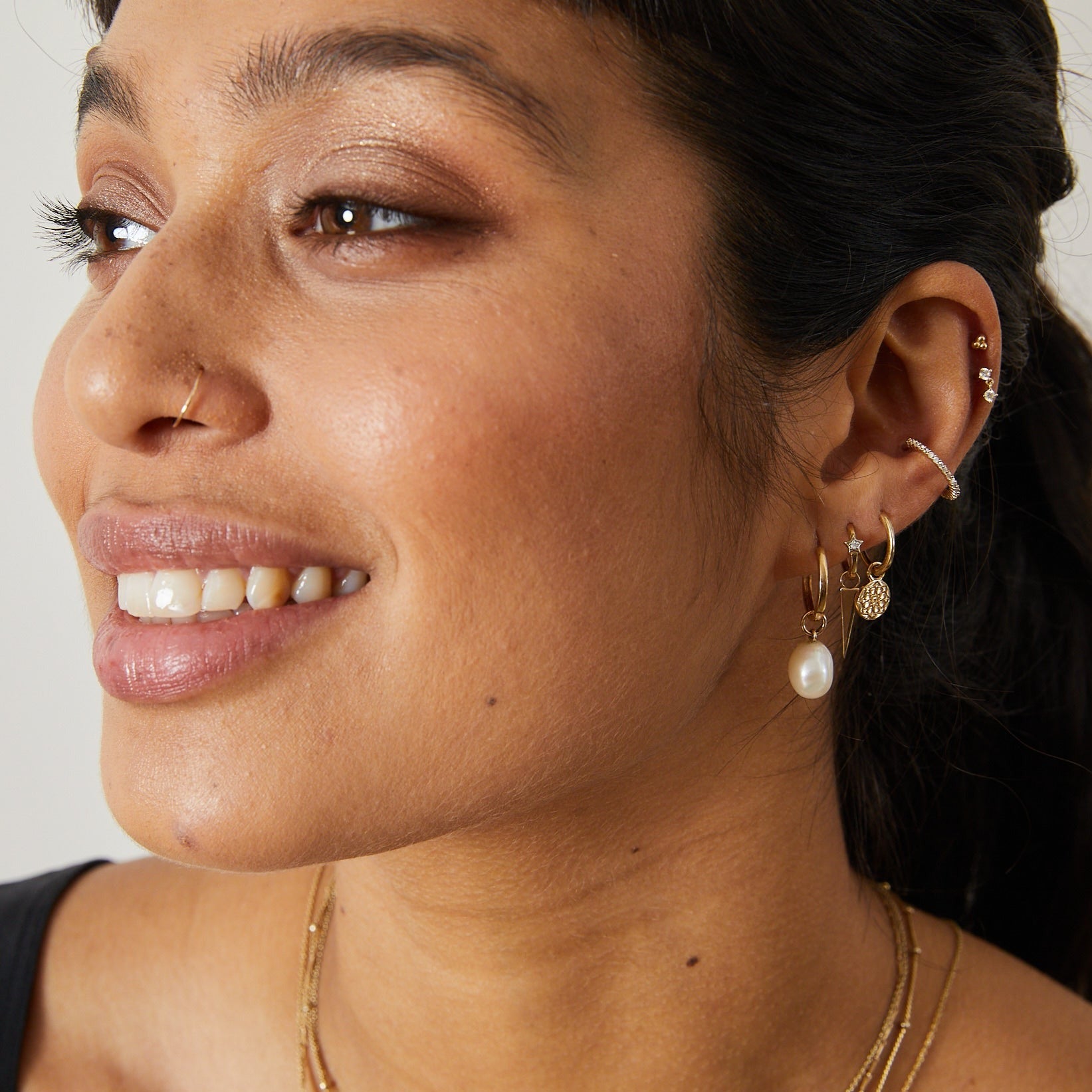 model wearing solid gold earring stack including the Spike Earring Charm 9k Gold