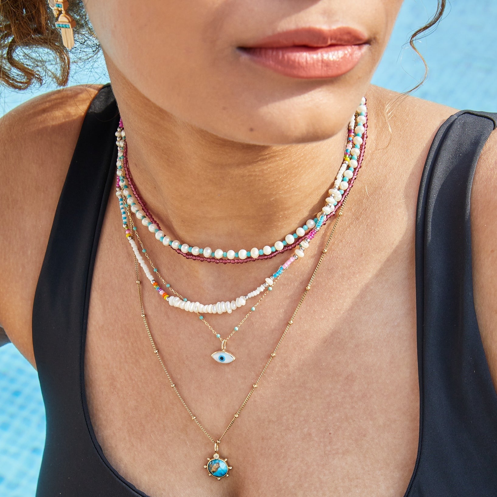 model in the pool wearing solid metal layered necklaces including the Pearl & Turquoise Necklace Sterling Silver