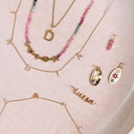 Solid gold jewellery on hard surface including the Personalised Birthstone Trio Pendant 9k Gold

