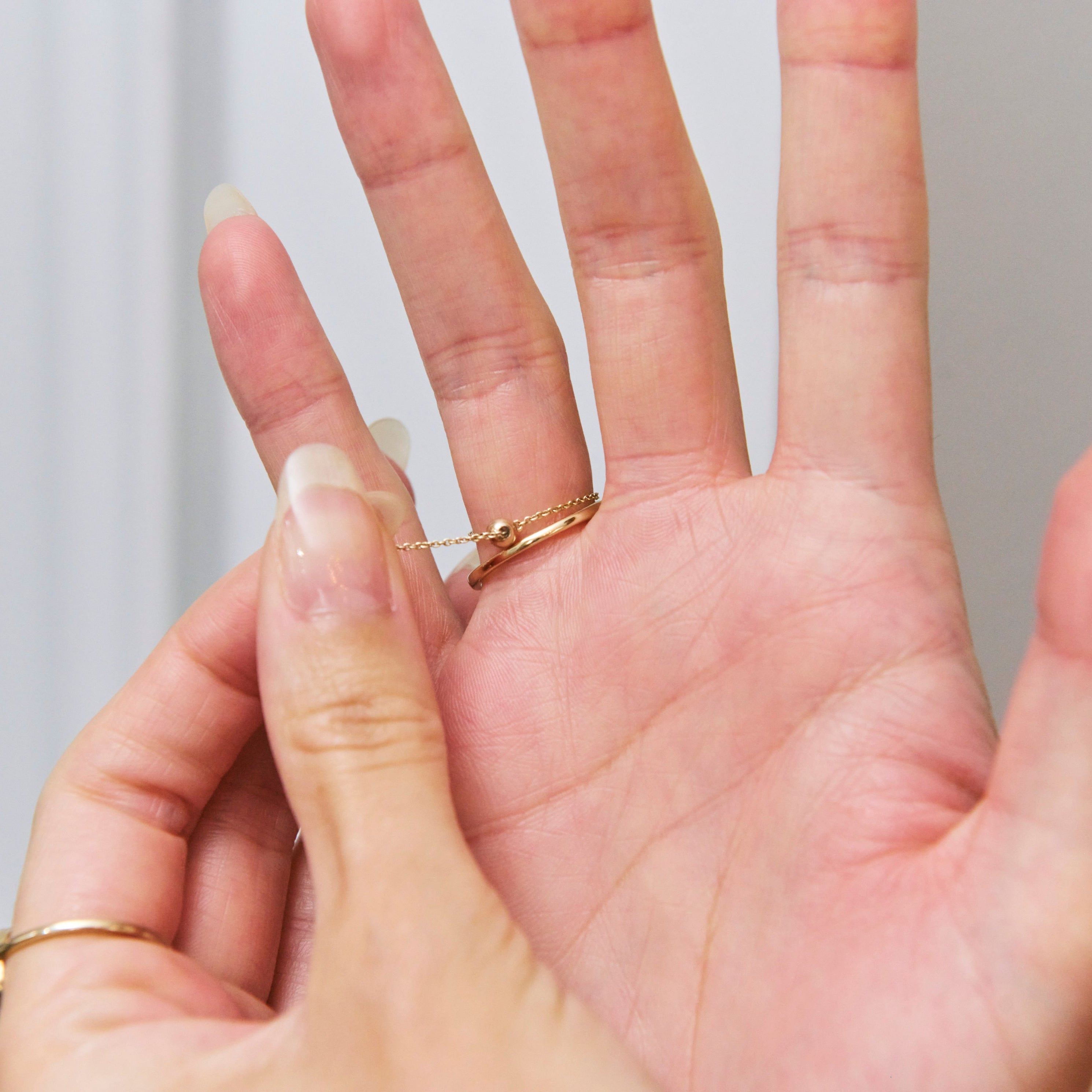Gold ring on a finger with a neutral background