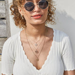 model wearing layered gold chakra pendants including the Heart Chakra Pendant 9k Gold