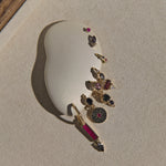Set of gold earrings with gemstones on a beige stone surface