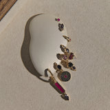 Set of gold earrings with gemstones on a beige stone surface
