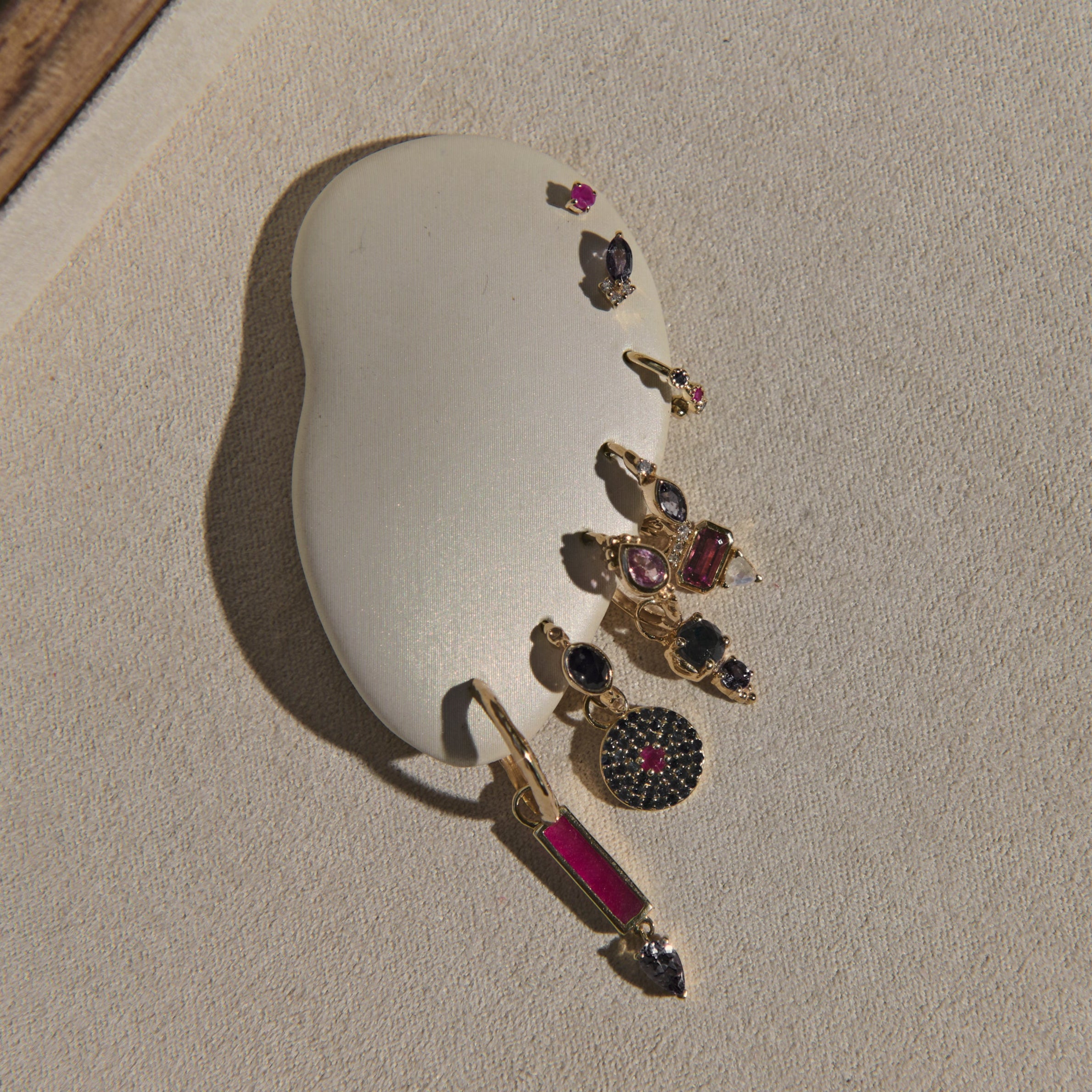 Set of gold earrings with gemstones on a beige stone surface