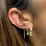 Close-up of an ear with multiple gold earrings and gemstones.