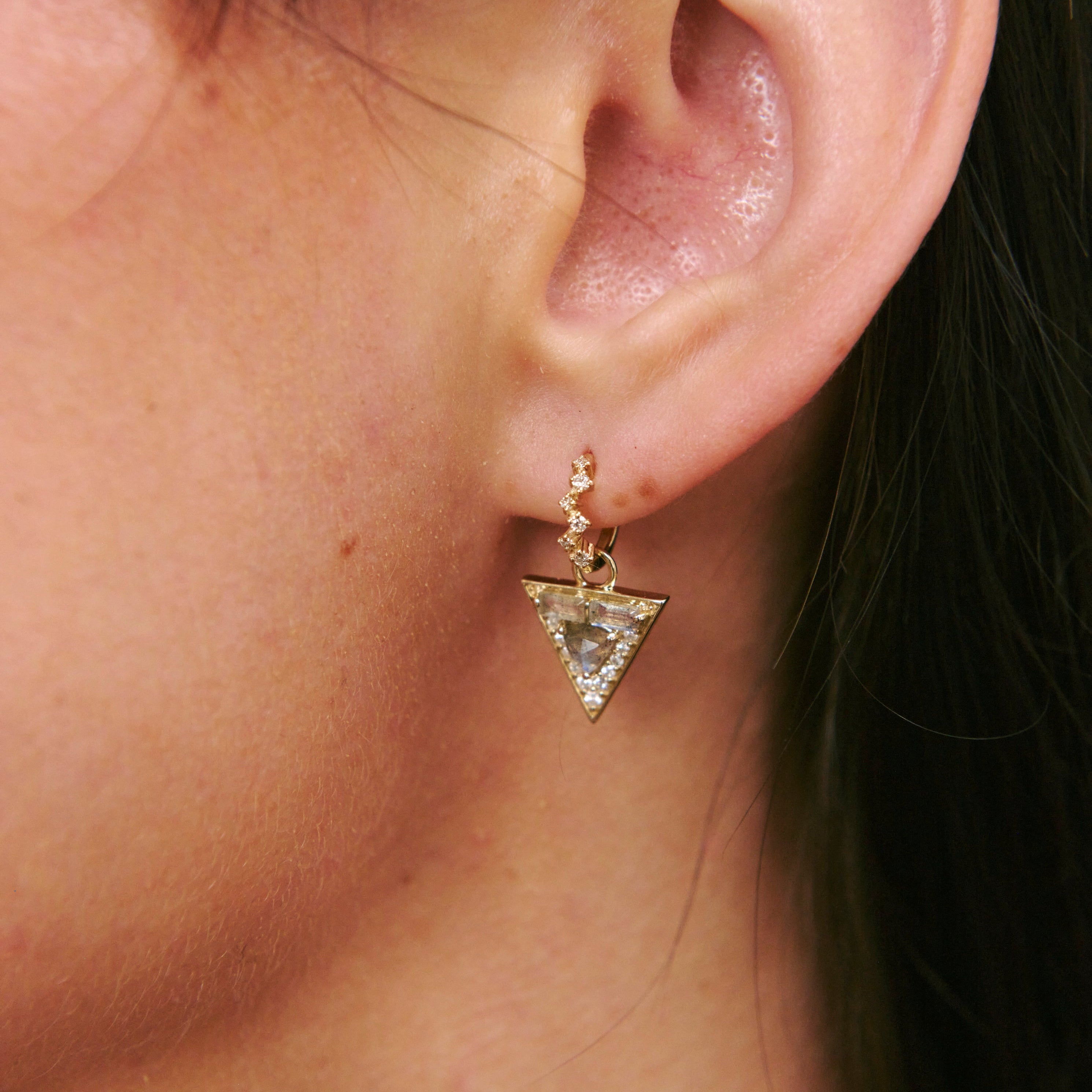 Close-up of an ear wearing a triangle-shaped earring.