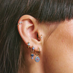 Close-up of an ear with multiple earrings against a neutral background