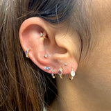 Close-up of an ear with multiple gold and gemstone earrings.