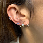 Close-up of an ear with multiple gold earrings featuring gemstones.