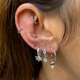 Close-up of an ear with multiple silver earrings and a nose ring.