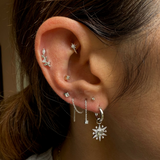 Close-up of an ear with multiple silver earrings