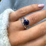 Close-up of a hand wearing a blue gemstone ring with a silver band.