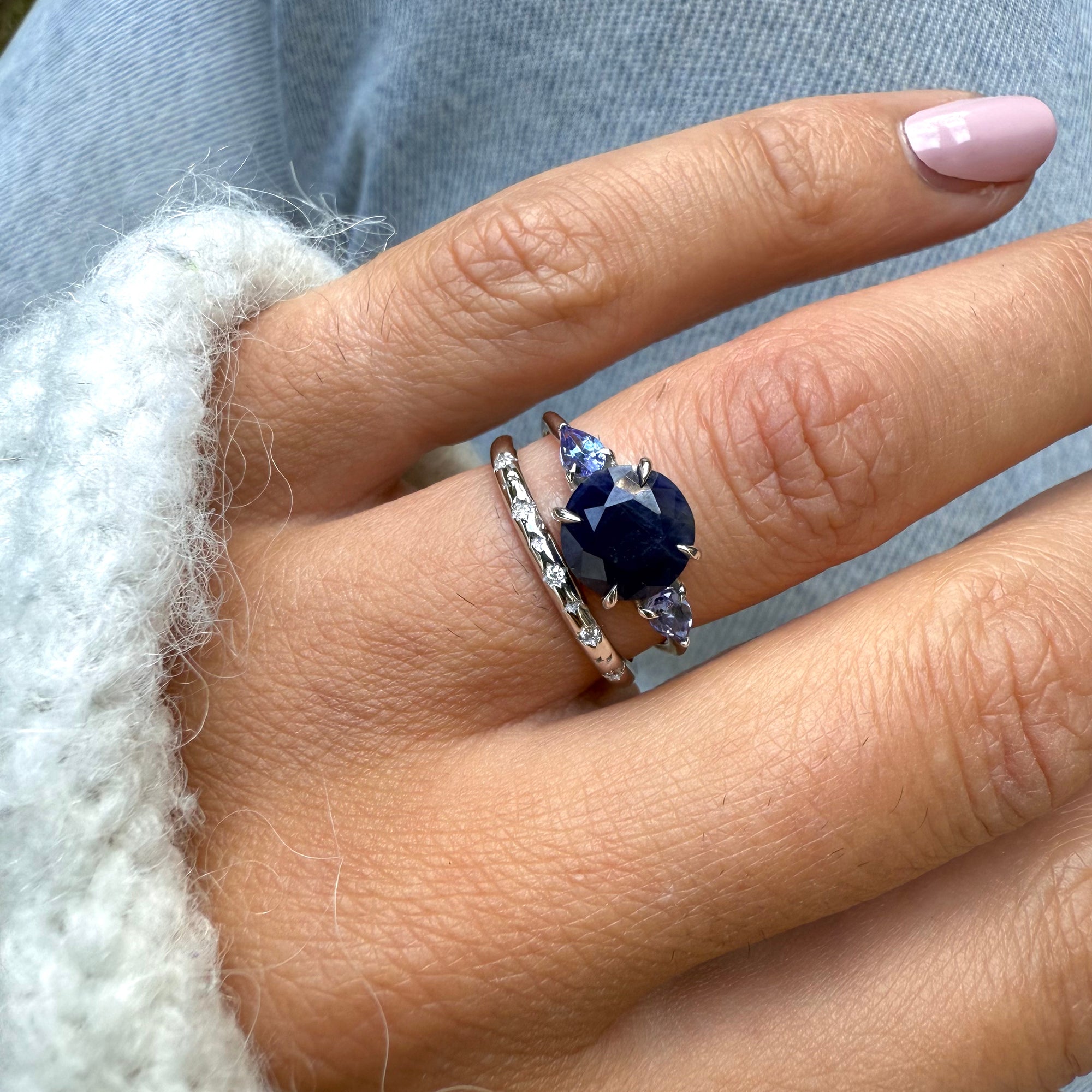 Close-up of a hand wearing a blue gemstone ring with a silver band.