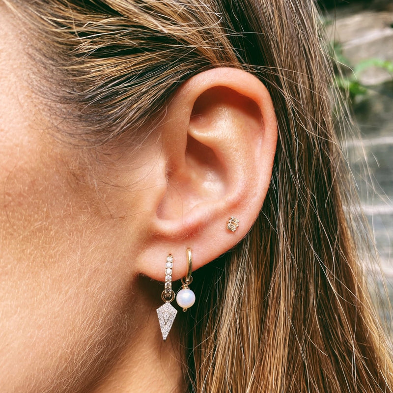 image of model wearing various earrings including diamond rhombus earring charm in 9k gold