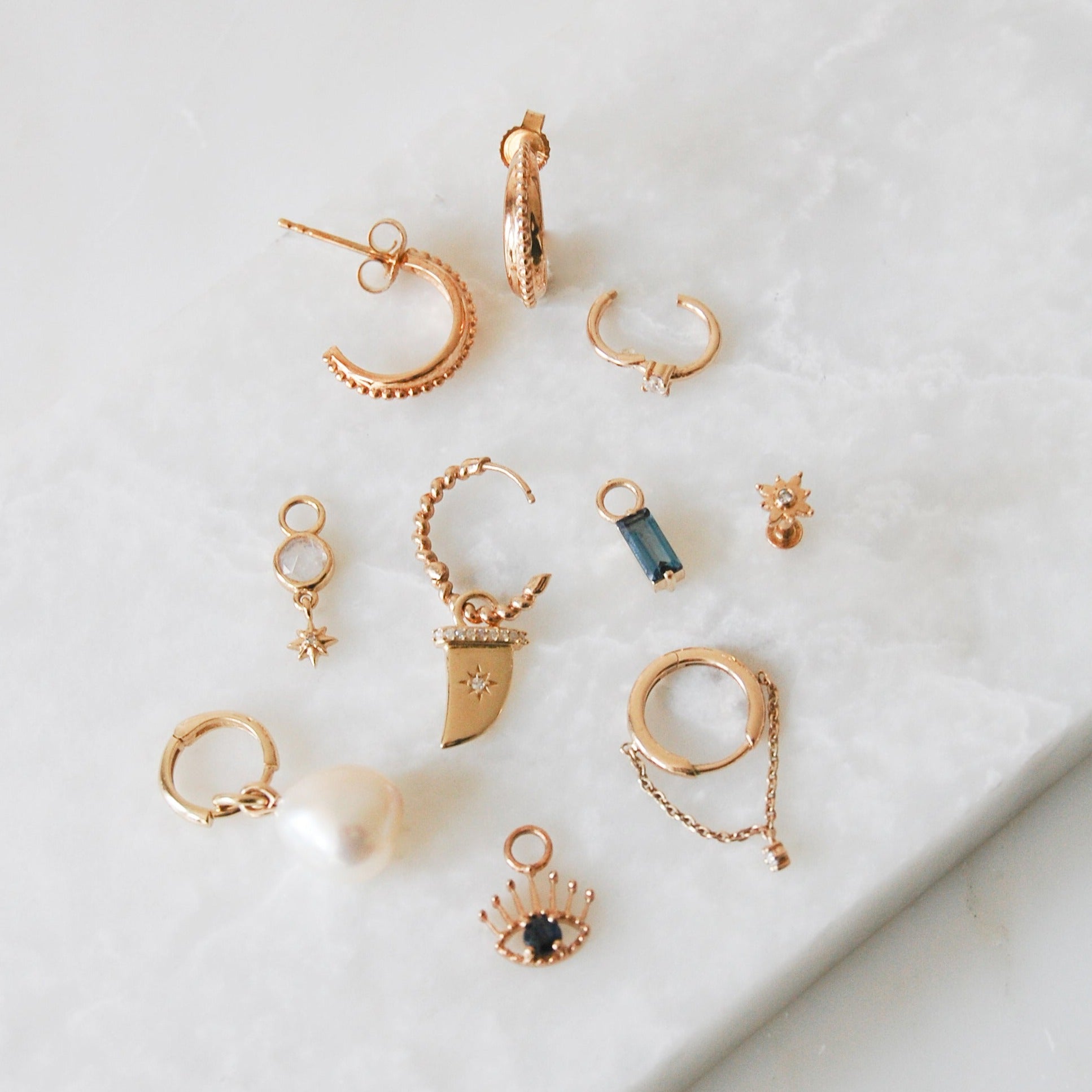 range of different earrings and charms including baroque pearl in 9k gold